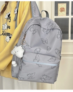 Detailed view of butterfly pattern on light grey backpack with white cloud plush pendant