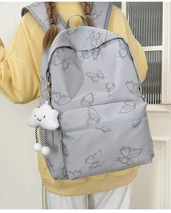 Detail of light grey backpack with butterfly print and plush cloud charm accessory