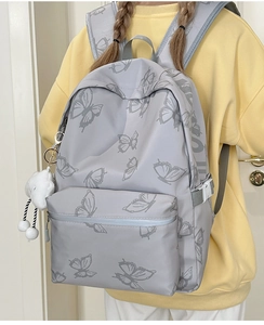 Macro detail of butterfly print school backpack with side buckle and plush cloud charm
