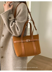 Gros plan d'un sac seau rétro marron porté par un mannequin en manteau gris élégant