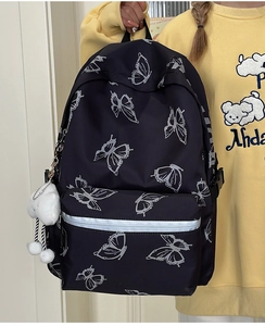 Detail of black butterfly backpack with reflective strip and white plush ball charm