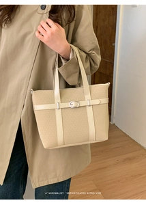 Détail d'un sac crème en texture tissée avec boucle métallique et doubles poignées