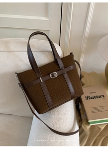 Détail d'un sac cabas marron en tissu à motifs et finitions cuir sur un canapé