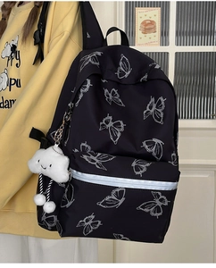 Detail of black backpack with white butterfly print and plush smiley cloud charm