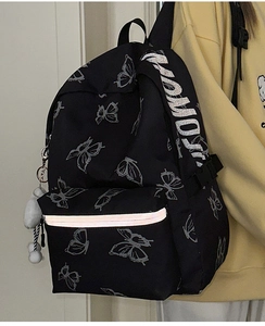 Close-up of black backpack featuring silver butterfly print and reflective safety strip