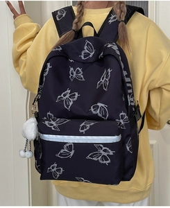Detail of black butterfly print backpack with waterproof fabric and white plush pom-pom