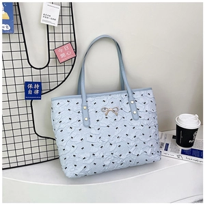 Detailed view of light blue tote bag with ribbon prints and golden bow hardware