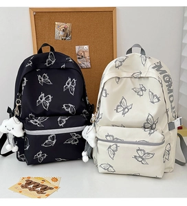 Detail of butterfly print backpacks in black and beige with cute cloud plush charms