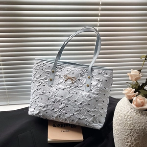 Polka dot tote bag with black bows and blue handle shown in soft natural sunlight