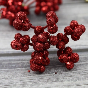 Close-up of glittery red Christmas berry clusters on rustic grey wooden background