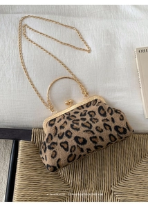 Detailansicht der Muscheltasche mit Leopardenmuster, Goldrahmen und Kettenriemen auf Stuhl