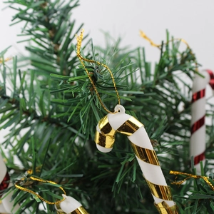 Detail eines Zuckerstangen-Ornaments mit gold-roten Streifen an einem Weihnachtsbaumzweig