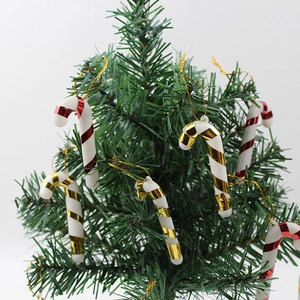 Detail von rot und gold gestreiften Zuckerstangen-Anhängern an einem grünen Weihnachtsbaum