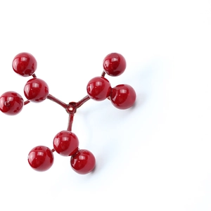 Detailed close-up of shiny artificial red Christmas berries for holiday tree DIY wreaths