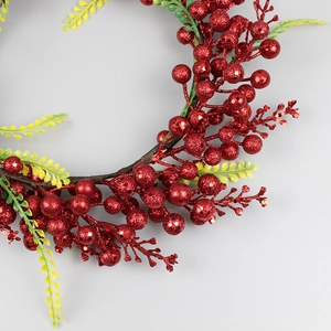 Weihnachtskranz mit glitzernden roten Beeren und grünem Laub auf braunem Astzweig