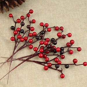Close-up of red artificial berries with glossy finish on rustic burlap and pine cones