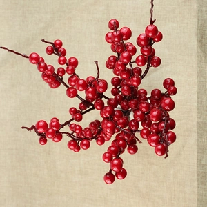 Close-up of glossy red berry stems on a textured beige fabric for holiday decoration