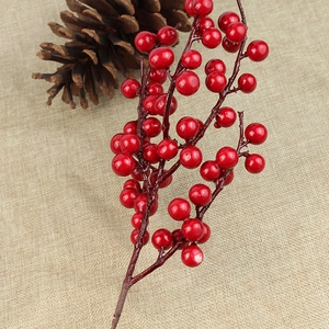 Artificial red Christmas berry stem on linen background with a natural pine cone decor