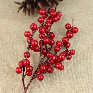 Artificial red Christmas berry stem on rustic linen background with a pine cone ornament
