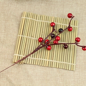 Close-up of artificial red and purple Christmas berry branches on a linen surface