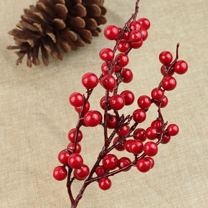 Close-up of artificial red berries spray with glossy finish on textured linen background