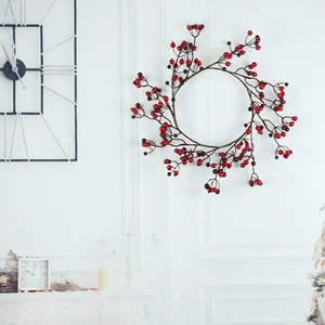 Detail of red berry Christmas wreath hanging on a white wall for festive home decor