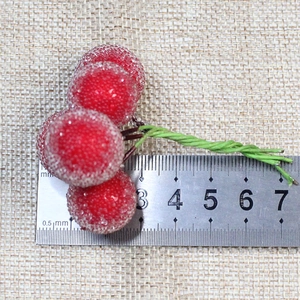 Close-up of frosted red berries with green wire stems and ice crystal texture on burlap