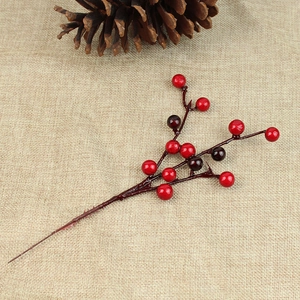 Close-up of red and dark purple artificial berry branch on rustic beige burlap background