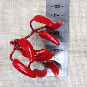 Detailed size reference showing 25-30mm mini artificial red chili peppers on a steel ruler