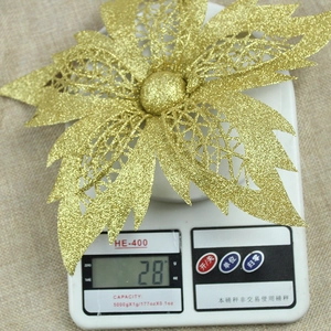 Close-up of 25cm gold artificial Christmas flower on scale showing weight details