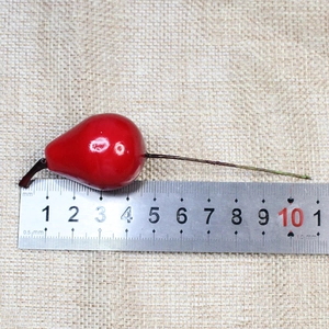Macro shot of artificial red foam berries with glossy coating on burlap with ruler scale