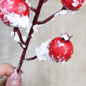 Close-up of artificial red holly berries with realistic snow texture for Christmas decor
