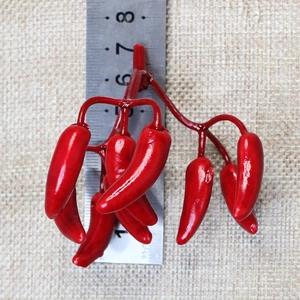 Close-up of artificial mini red chili peppers with ruler for scale on woven background