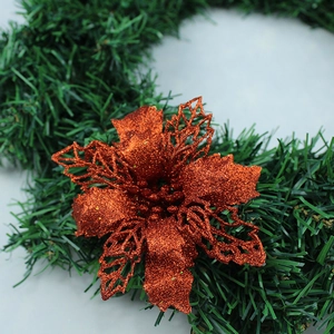 Macro shot of bronze glitter poinsettia flower on green Christmas tree branches