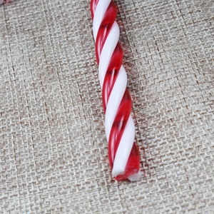 Detailansicht einer rot-weißen spiralförmigen Weihnachtszuckerstange auf rustikaler Sackleinen