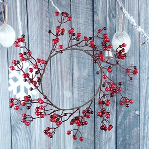 Close-up of vibrant red berry Christmas wreath on a rustic blue wooden background