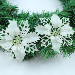 Close-up of white glitter hollow poinsettia flowers on green pine branch decor