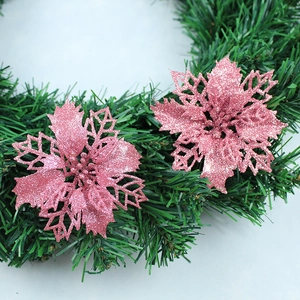 Close-up of pink glitter poinsettia artificial flowers on a green Christmas wreath