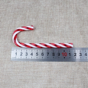 Detail von rot-weiß gestreifter Zuckerstange auf Jute mit Lineal für Größenangabe
