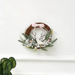 Christmas wreath detail with pink ribbons, white bird, and antlers on natural rattan