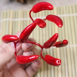 Close-up of bright red artificial mini chili peppers cluster on a bamboo mat background