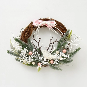 Detail of Christmas wreath with green needles, white berries, and a mesh bird ornament