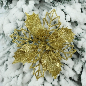 Golden glitter artificial Christmas flower ornament on snowy pine tree branches