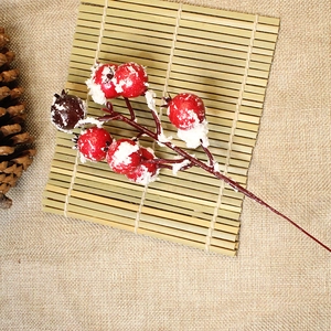 Artificial winter holly red berries with artificial snow on rustic burlap background