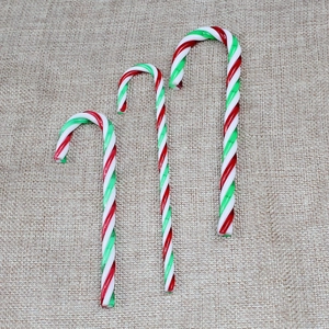 Drei rot-grün-weiße gestreifte Zuckerstangen-Ornamente als Weihnachtsdeko auf Jute