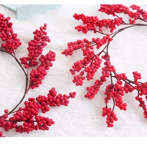 Close-up of artificial red berry branches for Christmas decor on white fur background