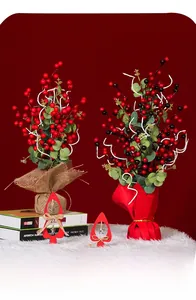 Dettaglio di bonsai con bacche rosse artificiali in juta e confezione festiva in seta