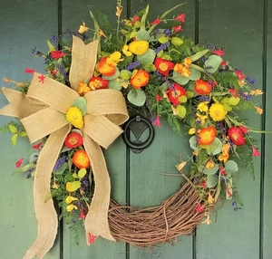 Rustic floral wreath with yellow poppies and burlap bow on a green wooden door