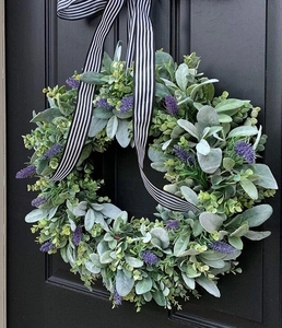 Detail of lavender and eucalyptus wreath with black and white ribbon on a black door
