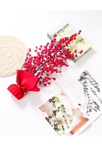 Close-up of decorative red faux berries with festive gold-tied red wrapping paper base